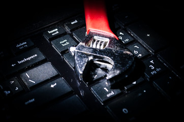 Wrench tool over a laptop on a dark background close up selective focus