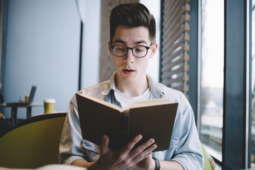 Handsome businessman reading a book in cafe