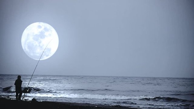 Fisherman on the Spanish beach with huge moon on the background.