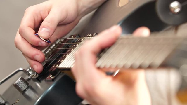 Male hands with electric guitar. Close up, part body adult person is holding instrument and playing. Hobby, music concept. 4K ProRes HQ codec