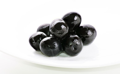 black olives on a white plate on a plate on a white background