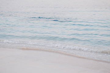 Closeup macro shot of sea ocean wave water with white foam, sandy beach background with copyspace....