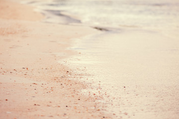 Closeup macro shot of sea ocean wave water with white foam, sandy beach background with copyspace. Toned with retro vintage film effect style filters, pastel faded colors