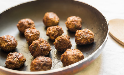 Cooked meatballs in a frying pan and wooden board
