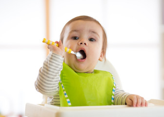 Happy baby boy spoon eats itself