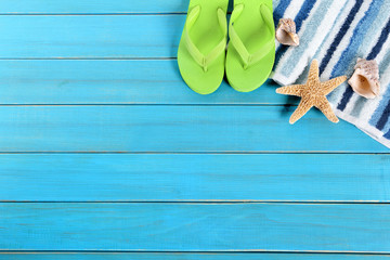 Beach background border striped towel flip flop sandals and starfish on old weathered blue wood...