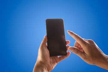 Hand holding phone mobile and touching screen isolated on blue background.