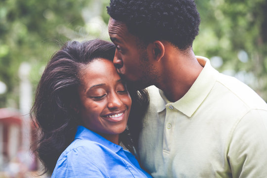 Closeup portrait of a young couple, guy in yellow shirt kissing woman with blue shirt, happy moments, positive human emotions on isolated outdoors outside background.