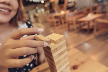 Asian woman having fun playing Jenga at the coffee shop in selective focus.