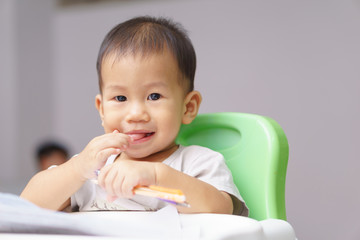 Asian boy about 1 year and a month learning write with pen and paper