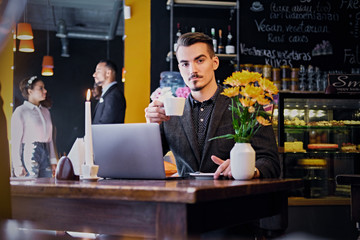 A man drinks coffee in a cafe.