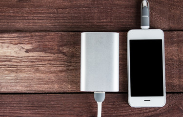 Charging Smartphone With Portable External Battery On A Wooden Background . Powerbank