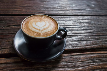 A Cup of hot latte art coffee on wooden table.