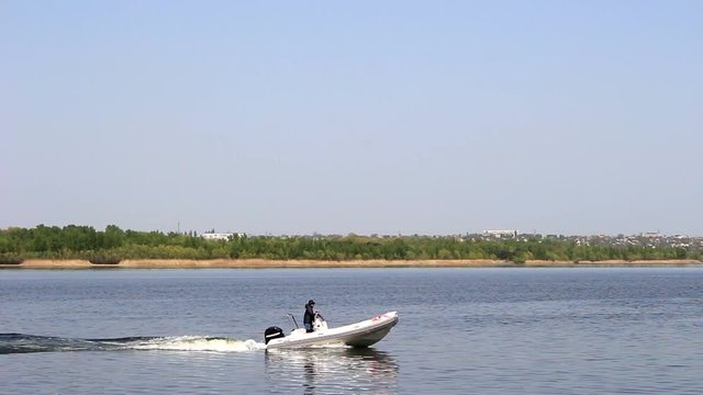 The motor boat sails along the river, the helmsman looks through binoculars.
