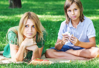 Family breakfast on grass. Mom and son eating sandwich