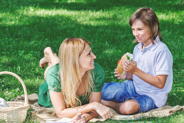Family breakfast on grass. Mom and son eating sandwich