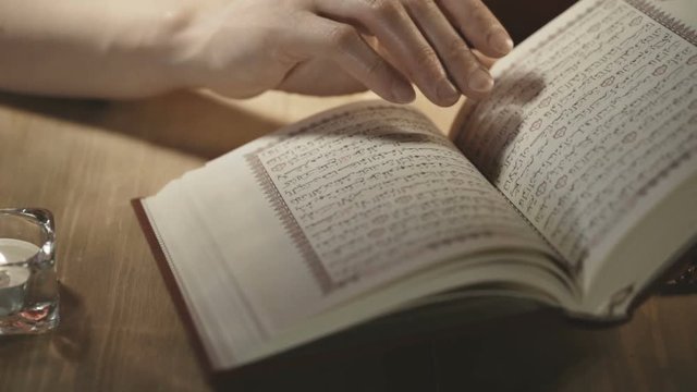 Women's hands leaf through the pages of the Koran