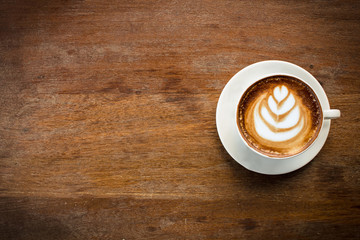 A Cup of hot latte art coffee on wooden table.