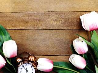 alarm clock with beautiful bouquet of tulips on wooden background