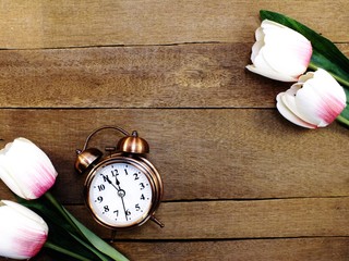 alarm clock with beautiful bouquet of tulips on wooden background