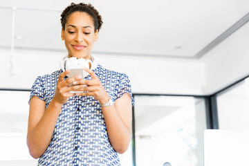 Portrait of smiling afro-american office worker with her mobile phone in offfice
