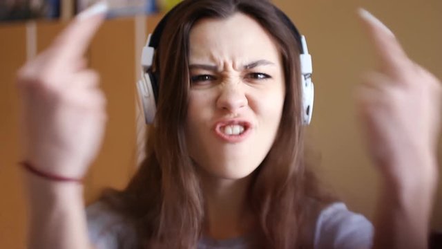 A young mature girl screaming at the screen I hate you. And shows the middle finger. A difficult teenager from an unhappy family .POV view at young blonde enraged woman shouting with anger and crying