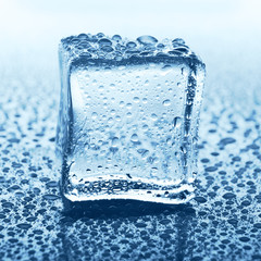 Transparent ice cube with reflection on blue glass with water drops