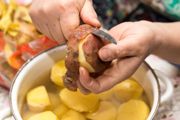 The cook cleans the potatoes with a knife