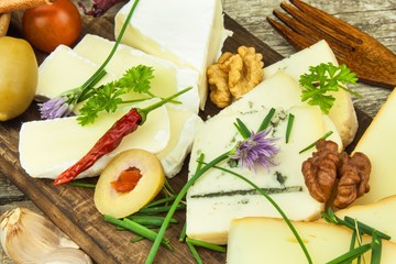 Refreshments from different types of cheese. Healthy breakfast of dairy products. Sliced cheeses on a wooden table.