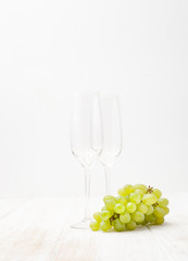 brush of green grapes and glasses on white