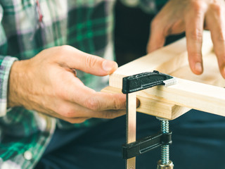 Man crafting wooden chair object keeping wooden boards in hands. Do it yourself project making process. Using press vise