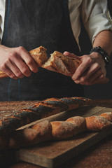 Male hands break the baguette