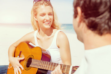 Fototapeta na wymiar Beautiful young woman playing guitar on beach