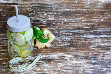 Detox infused water  with lime, lemons and ginger in mason jar on wooden background. Delicious...