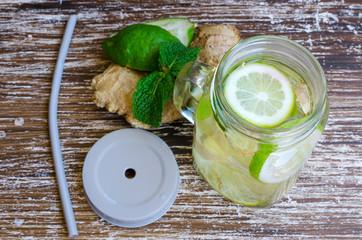 Detox infused water  with lime, lemons and ginger in mason jar on wooden background. Delicious refreshing, summer drink. Healthy lifestyle, detox diet, loss weight concept.