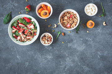 Breakfast with muesli, strawberry salad, fresh fruit, nuts on grunge background. Healthy food concept. Flat lay, top view