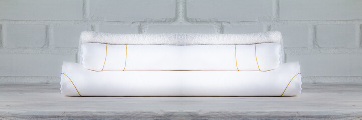 Luxury white bed sheets stacked on loft background. Closeup. Copy space.