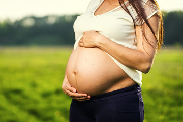 Photo of pregnant woman belly. Hands hugging pregnant belly. Close up of human hands holding pregnant belly. Pregnant woman hugs her belly. Pregnancy. Pregnancy Concept