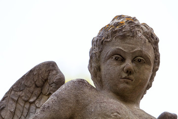 Children angel statue in city cemetery isolated with white background, close up. Old cemetery with...