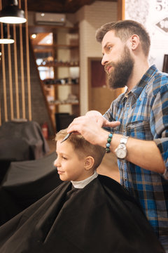 Serious male barber working with a young boy