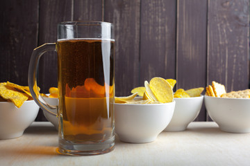 Lager beer in glass and potato chips on wooden background
