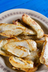 Flat lay above fried chicken breasts on the plate above blue wooden planks board