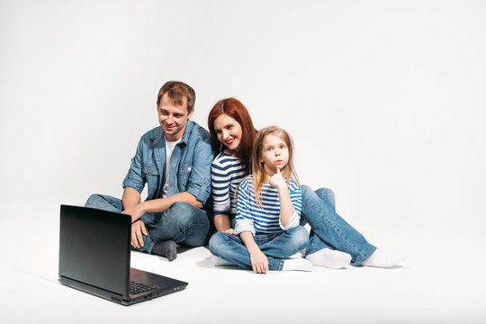 Happy family Father, mother and child lying on the floor with laptop on white background isolated