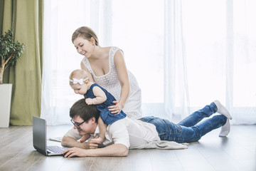 Family mom, dad, and daughter with a laptop together at home happy