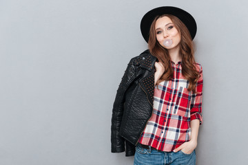 Young stylish girl wearing plaid shirt and chewing bubble gum