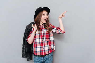 Woman in hat and plaid shirt pointing finger away