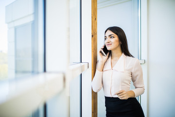 Portrait of a young business woman speak at phone against panoramic windows