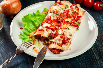 Traditional mexican enchiladas with chicken meat, spicy tomato sauce and cheese on a plate