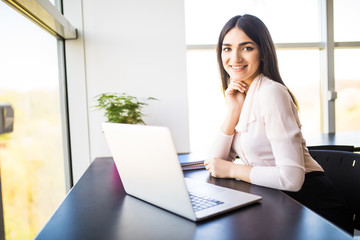 Portrait of businesswoman in sweater sitting at her workplace in office