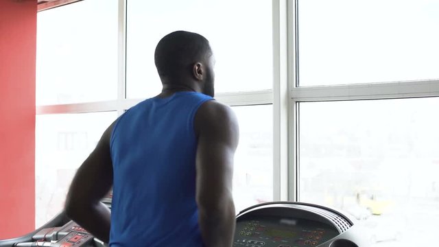 African-American male boxer running on treadmill and exercising in the gym